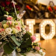 Hochezeitliche Deko: Blumen, im Hintergrund der Schriftzuge „Love“